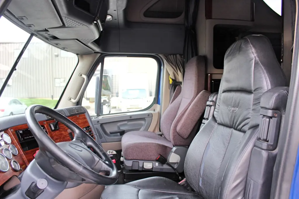 2020 Freightliner Cascadia 125 Glider – driver and passenger seats with woodgrain dashboard interior.