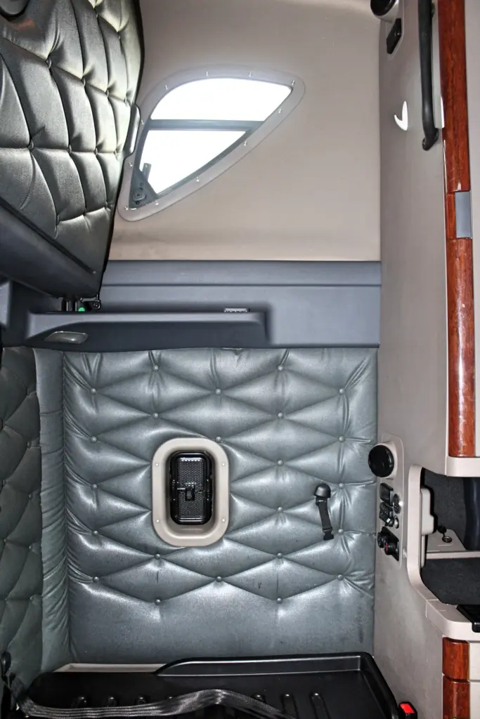 2020 Freightliner Cascadia 125 Glider – sleeper interior with quilted padded walls, side window and bunk area.