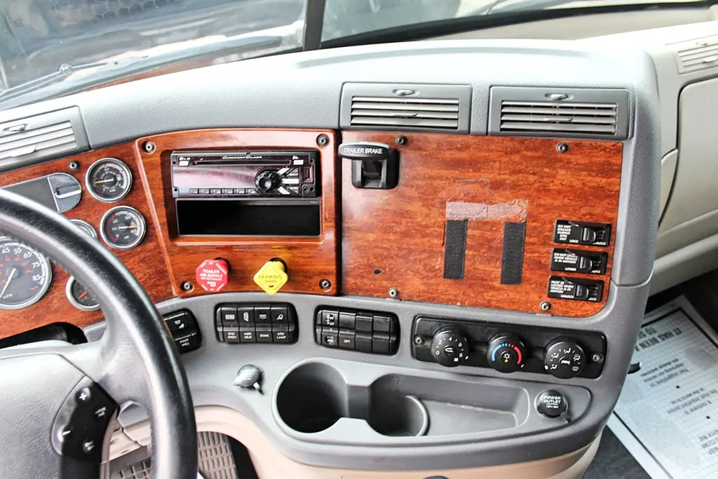 2020 Freightliner Cascadia 125 Glider – woodgrain dashboard, radio, climate controls and center console close-up.