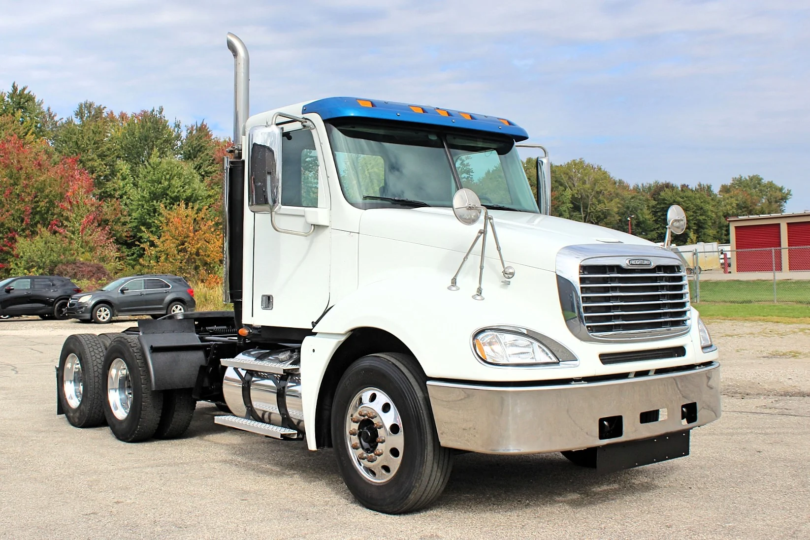 2020 Freightliner Columbia 120 — front three-quarter view of white day cab with blue roof fairing and chrome grille.
