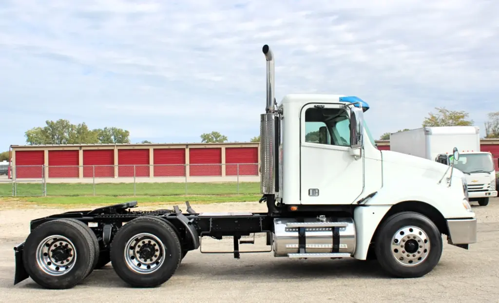2020 Freightliner Columbia 120 — side profile of white day cab tractor with chrome stack and polished aluminum wheels.