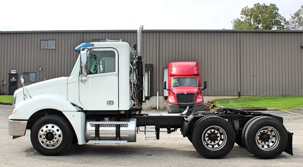 2020 Freightliner Columbia 120 — bare-frame side view of white tractor, no trailer, tandem rear axles and aluminum wheels.