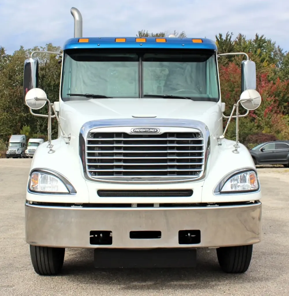 2020 Freightliner Columbia 120 — straight-on view of white day cab with blue roof fairing and polished front bumper.