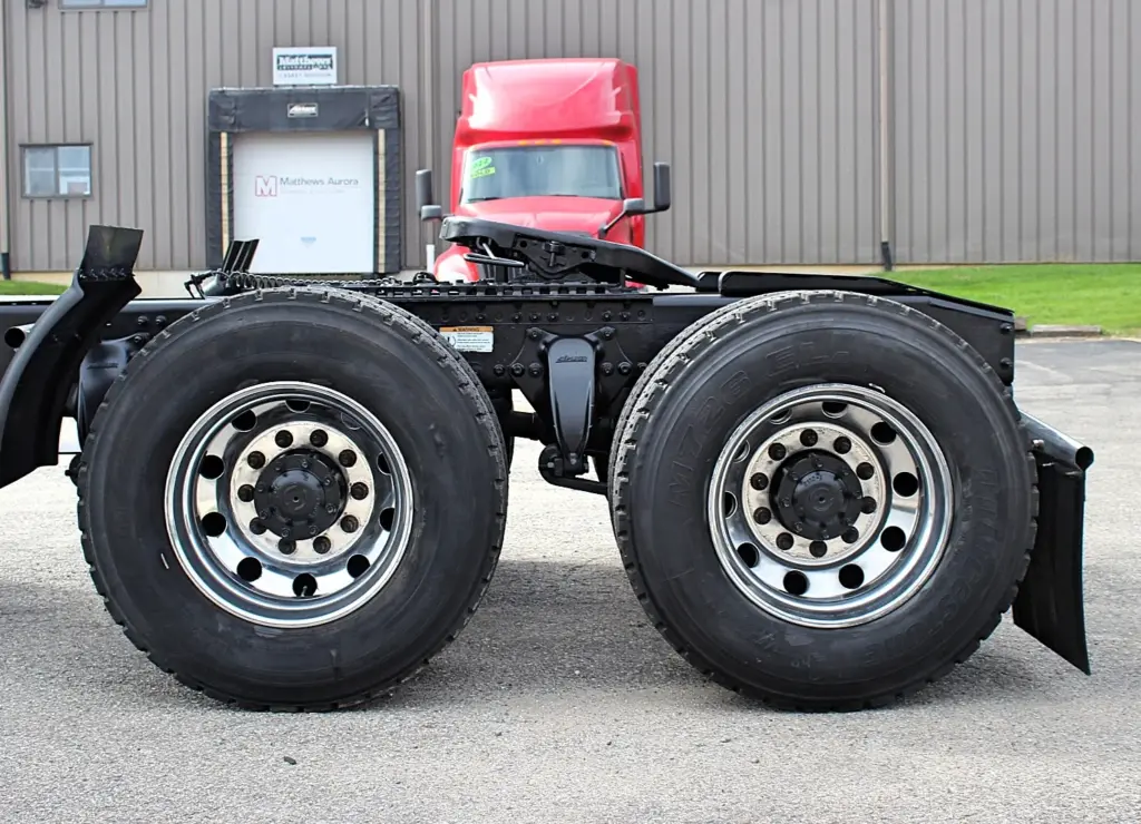 2020 Freightliner Columbia 120 — side view of bare tandem rear axle chassis with aluminum wheels and dual tires.