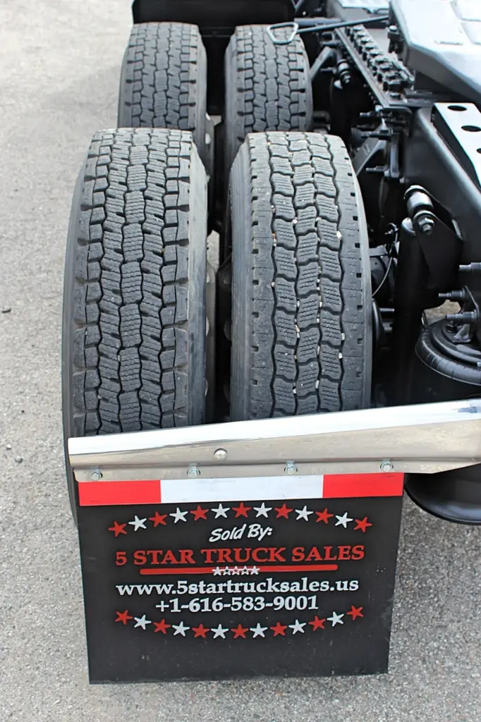 2020 Freightliner Columbia 120 — close-up of tandem rear tires with deep tread and chrome mudflap bar beside the axles.