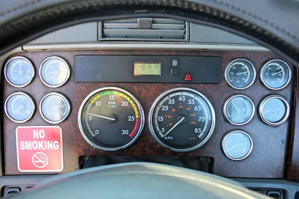 2020 Freightliner Columbia 120 — view past steering wheel at gauge cluster with tachometer, speedometer and air gauges.