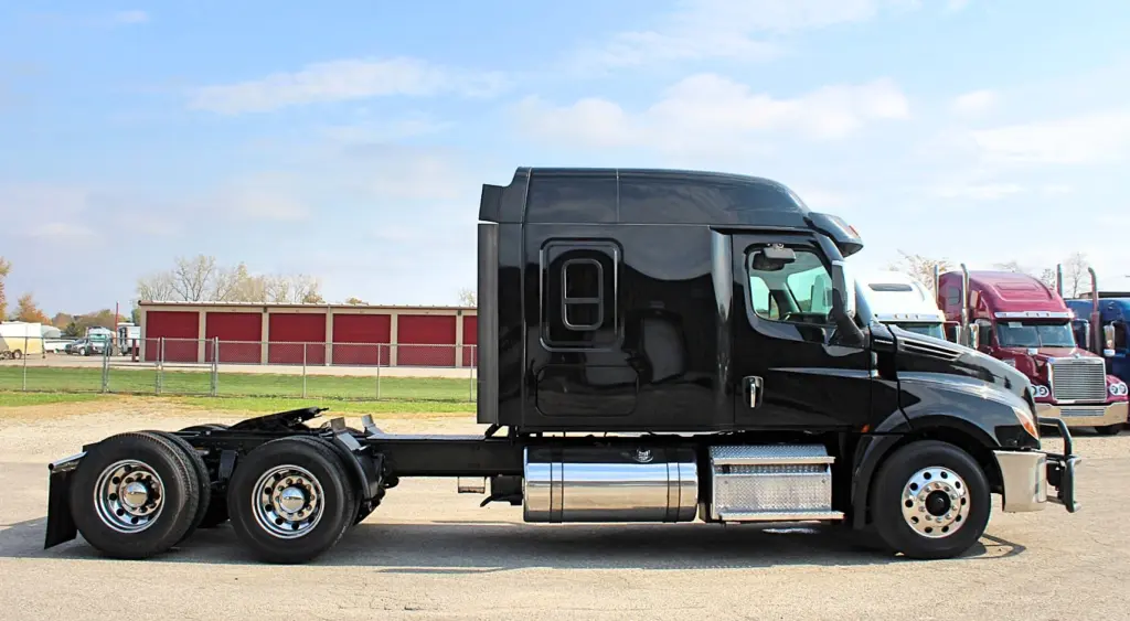 2021 Freightliner Cascadia 126 — side profile of black sleeper tractor with polished aluminum wheels and chrome fuel tank