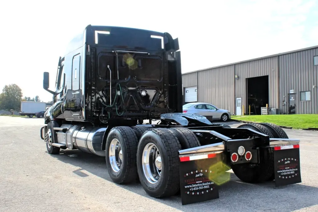 2021 Freightliner Cascadia 126 — angled rear view of black sleeper with polished aluminum tandem wheels and dual tires