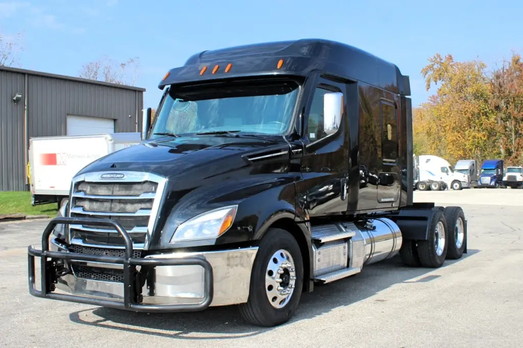 2021 Freightliner Cascadia 126 — driver-side angle showing black hood, bull bar, chrome bumper and steer wheel on paved lot
