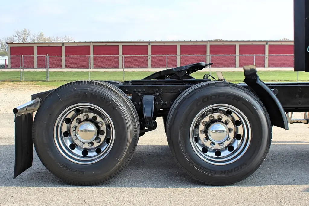2021 Freightliner Cascadia 126 — side view of rear tandem axle with polished aluminum wheels and black mudflap behind