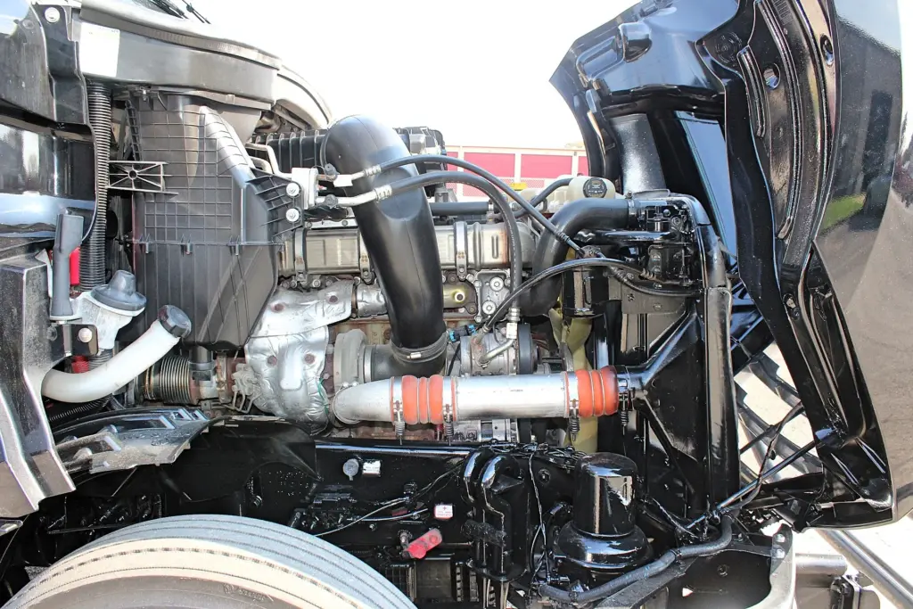 2021 Freightliner Cascadia 126 — engine bay with open hood, black intake tube and orange-clamped charge air pipe