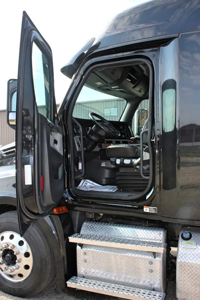 2021 Freightliner Cascadia 126 — open driver door showing black cab interior, steering wheel, seat and diamond plate steps