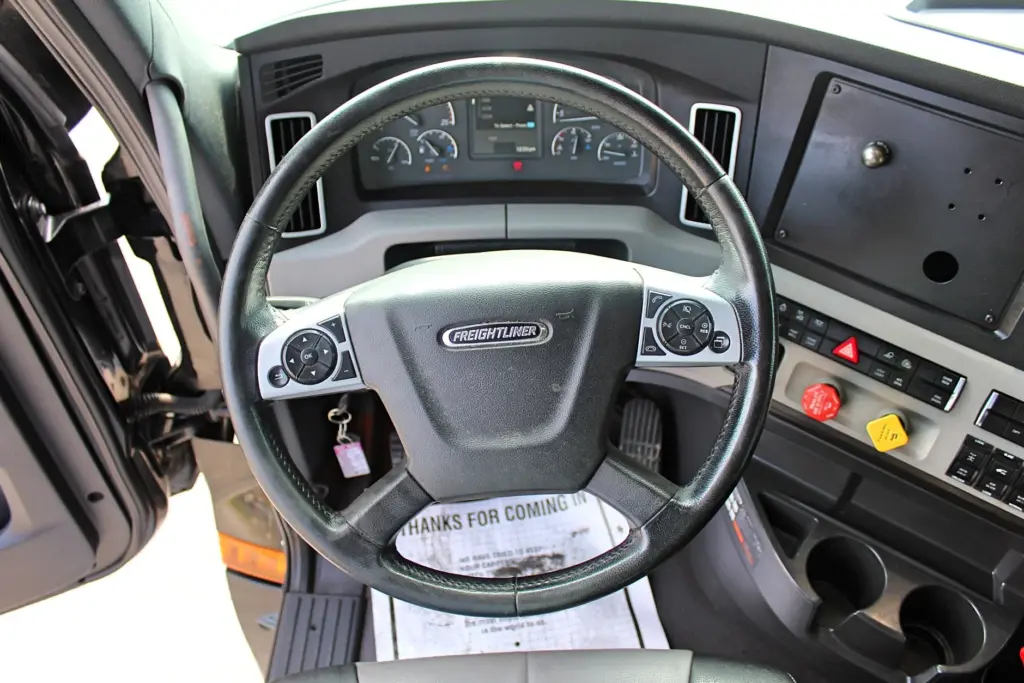 2021 Freightliner Cascadia 126 — close straight-on view of black leather steering wheel and Freightliner horn pad