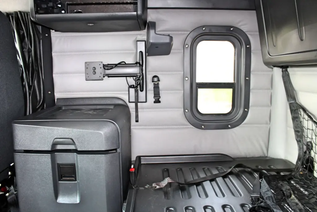 2021 Freightliner Cascadia 126 — gray leather-look sleeper wall with portrait window, tablet arm and black cooler box