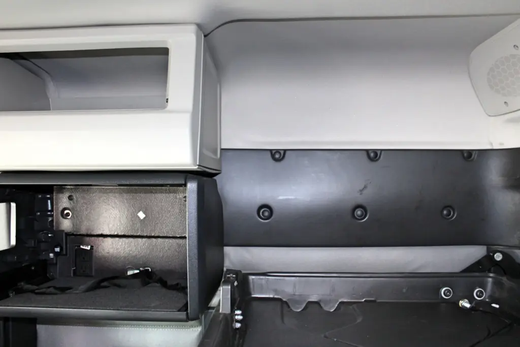 2021 Freightliner Cascadia 126 — angled view of gray overhead bin, black cabinet with power outlet and speaker grille