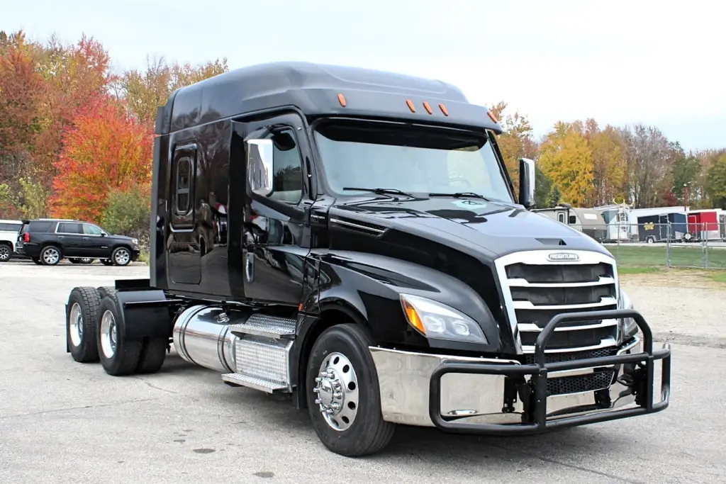 2021 Freightliner Cascadia 126 — front three-quarter view of black sleeper tractor, chrome grille and aluminum wheels.