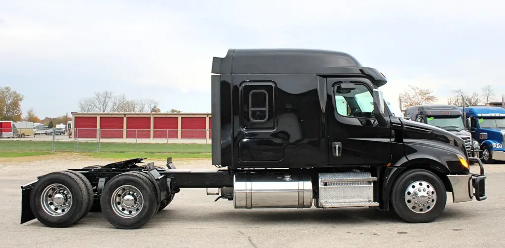 2021 Freightliner Cascadia 126 — side profile view of black sleeper tractor with aluminum wheels and chrome fuel tank.