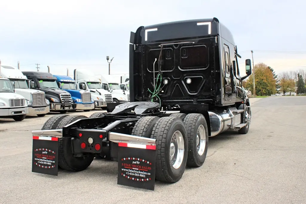 2021 Freightliner Cascadia 126 — rear three-quarter view of black sleeper cab, dual aluminum rear wheels and polished tank.