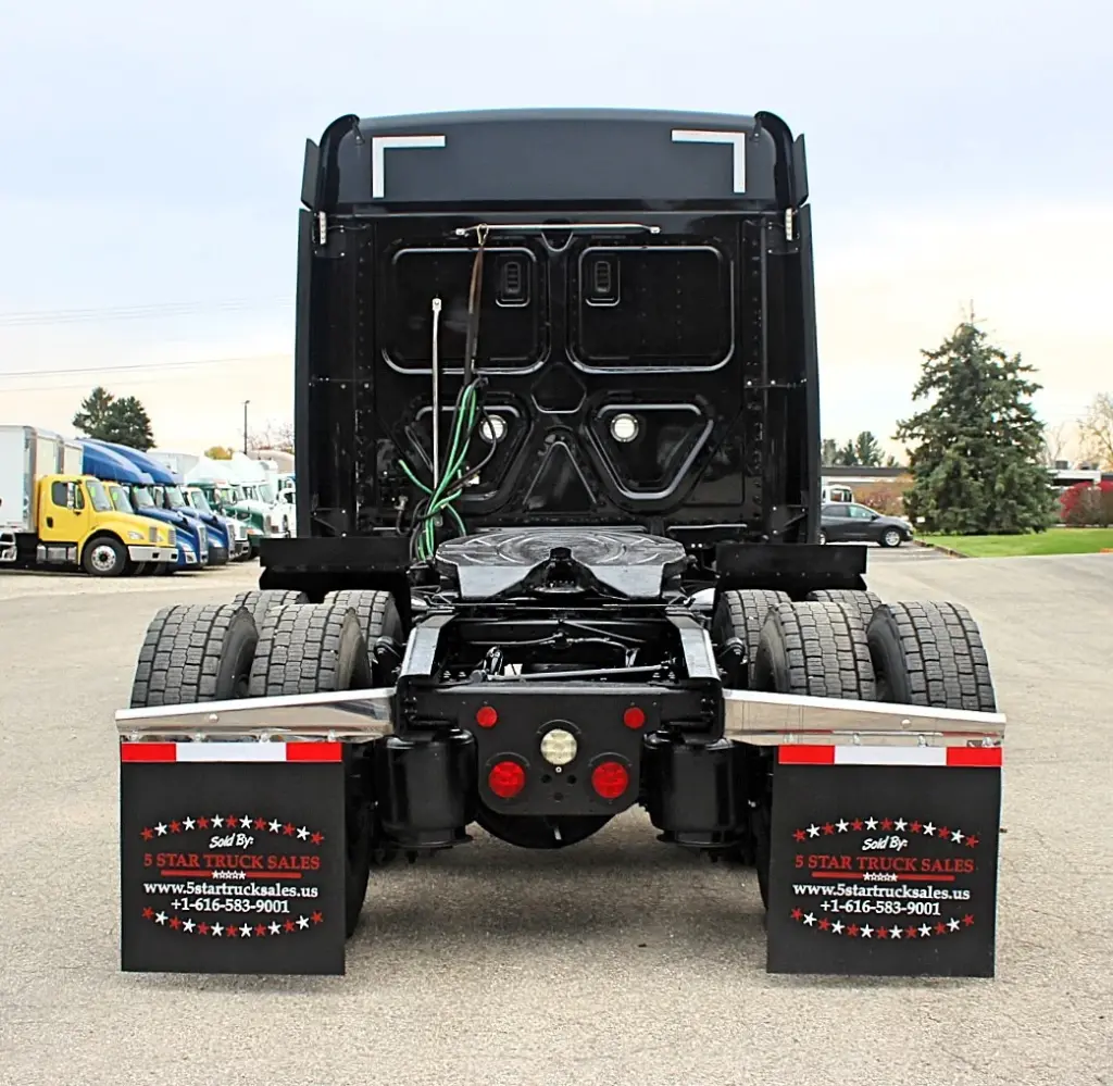 2021 Freightliner Cascadia 126 — straight rear view of black sleeper cab, tandem axles and red tail lights.