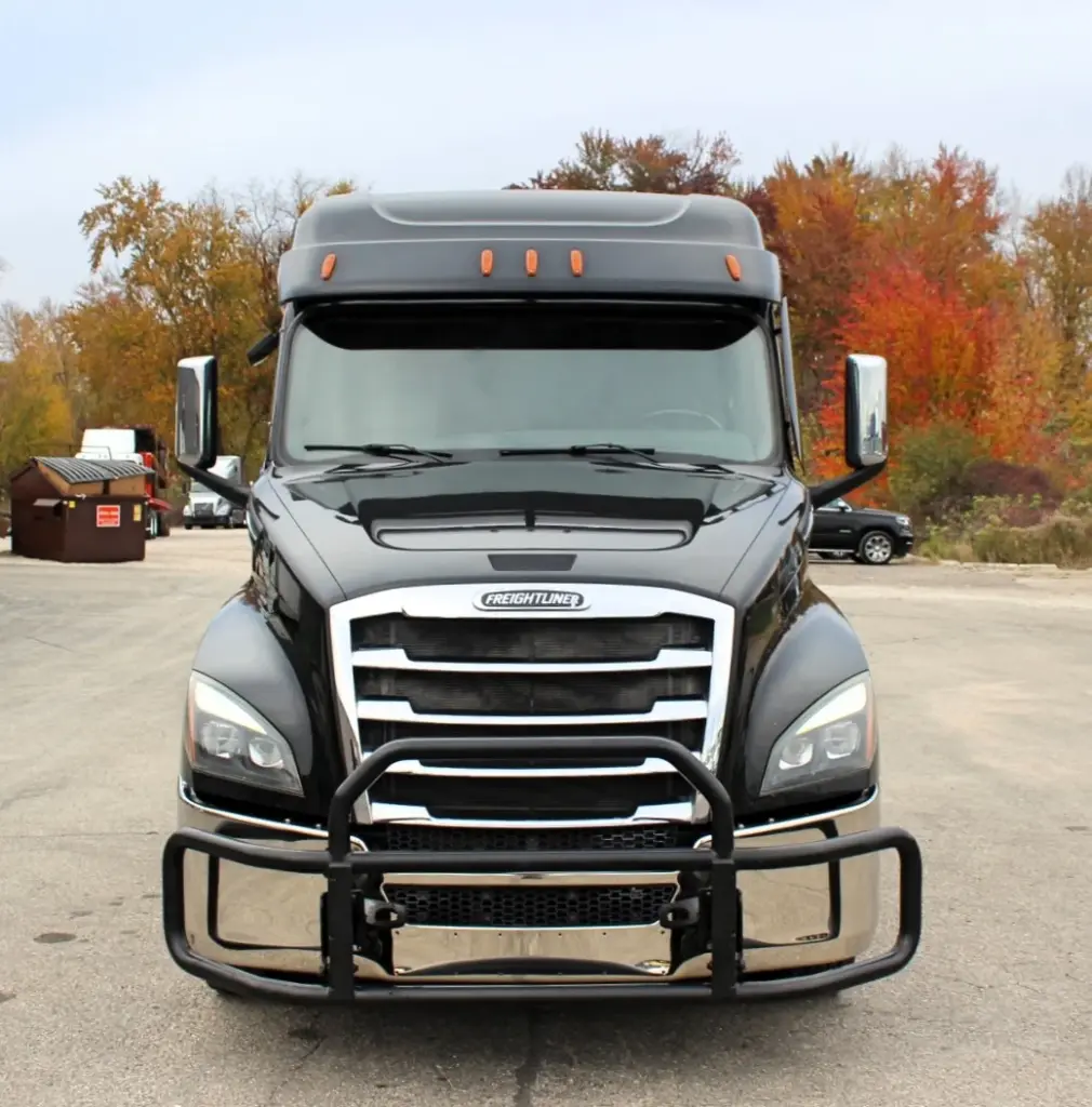 2021 Freightliner Cascadia 126 — front-facing view of black sleeper with chrome grille, bull bar and amber roof lights.