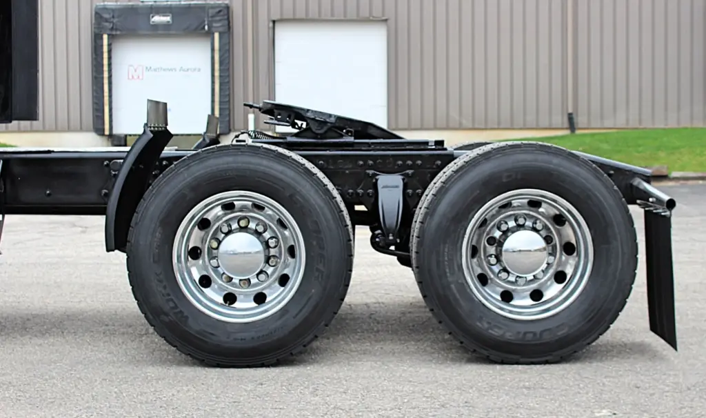 2021 Freightliner Cascadia 126 — side view of tandem axles with polished aluminum wheels and black frame rails.