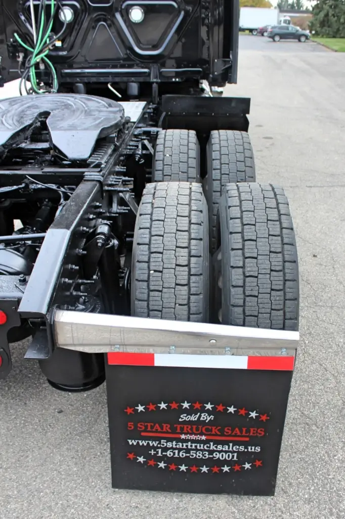 2021 Freightliner Cascadia 126 — low rear-quarter view of dual drive tires, black frame rails and aluminum-edged flap