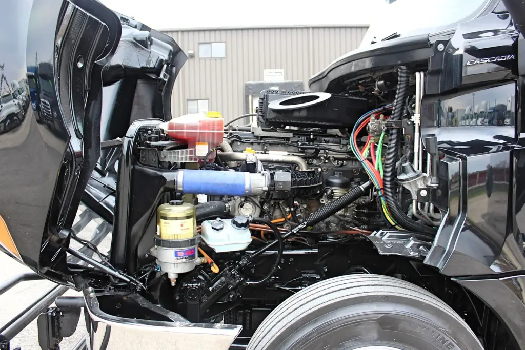 2021 Freightliner Cascadia 126 — engine bay under raised hood, DD15 with blue intake hose and fuel filter