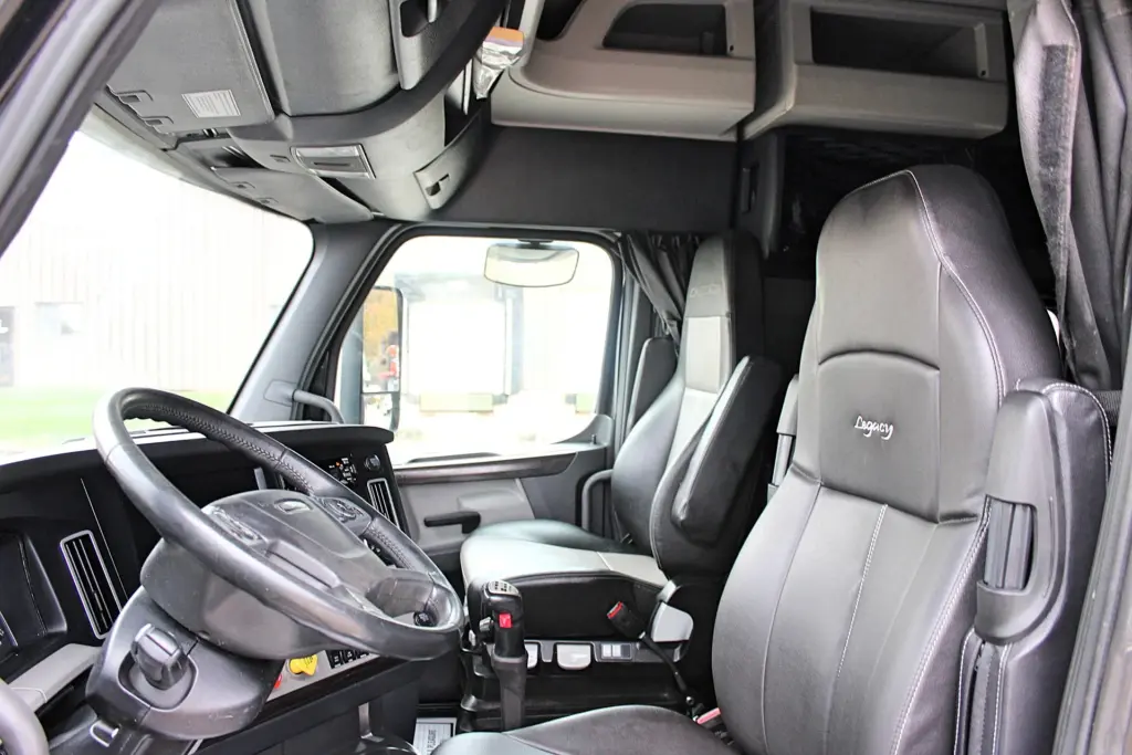 2021 Freightliner Cascadia 126 — interior view of cab with black leather seats and steering wheel facing forward.