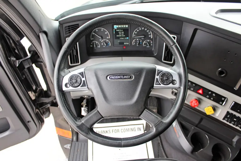 2021 Freightliner Cascadia 126 — close view of steering wheel, Freightliner horn pad and gauge cluster in cab.