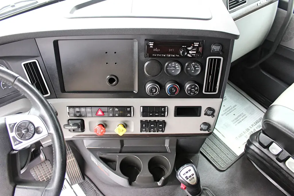 2021 Freightliner Cascadia 126 — center dash view of radio, gauges, switches and trailer brake above cup holders.