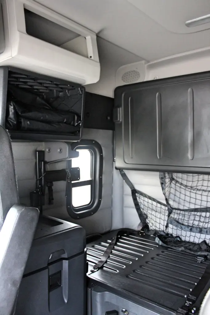2021 Freightliner Cascadia 126 — sleeper interior with bunk netting, overhead locker and side window.