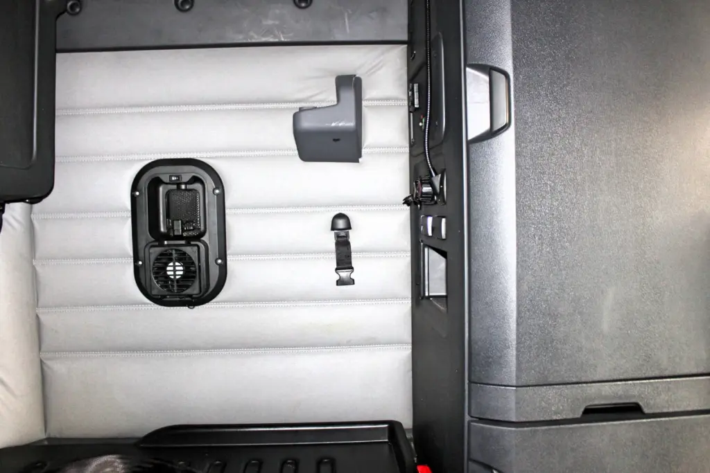 2021 Freightliner Cascadia 126 — overhead view of gray sleeper bunk with black vent fan, grab handle and seat belt buckle.