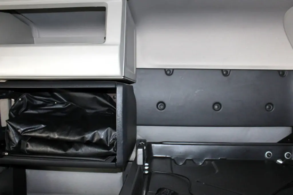 2021 Freightliner Cascadia 126 — close view of open black storage bin holding a leather pouch, gray trim